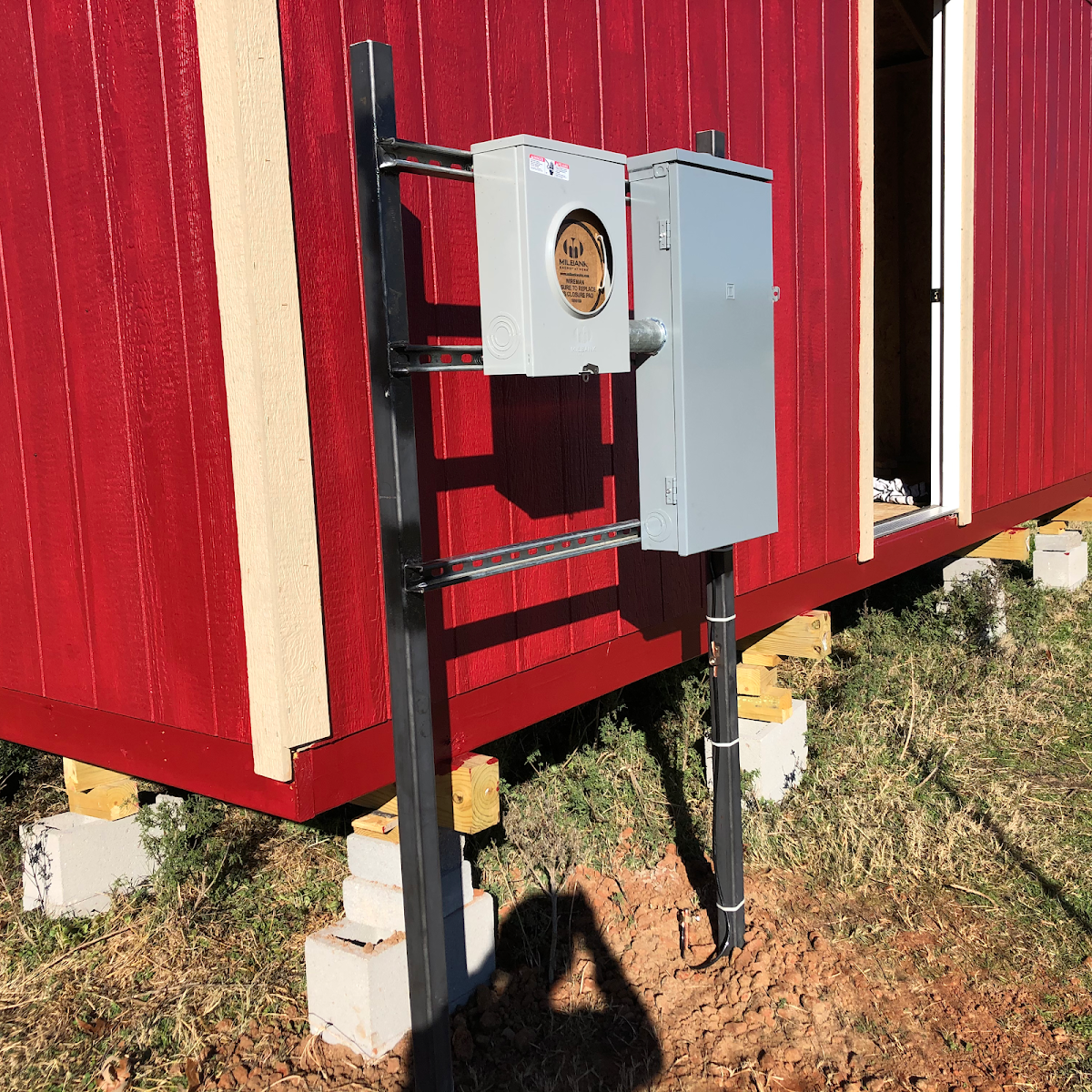 Electrical meter base installed on a red barn